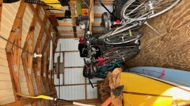 Three kayaks, three bicycles, three fishing poles in shed